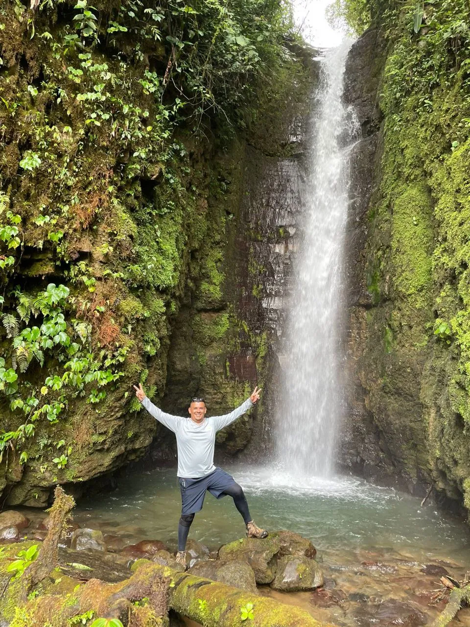 man smiling ear to ear in front of a waterfall
