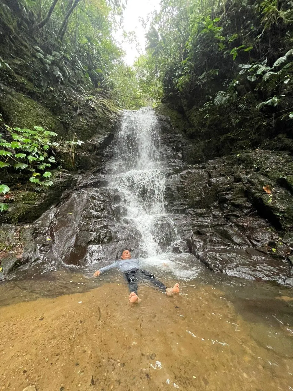 man swimming in a waterfall