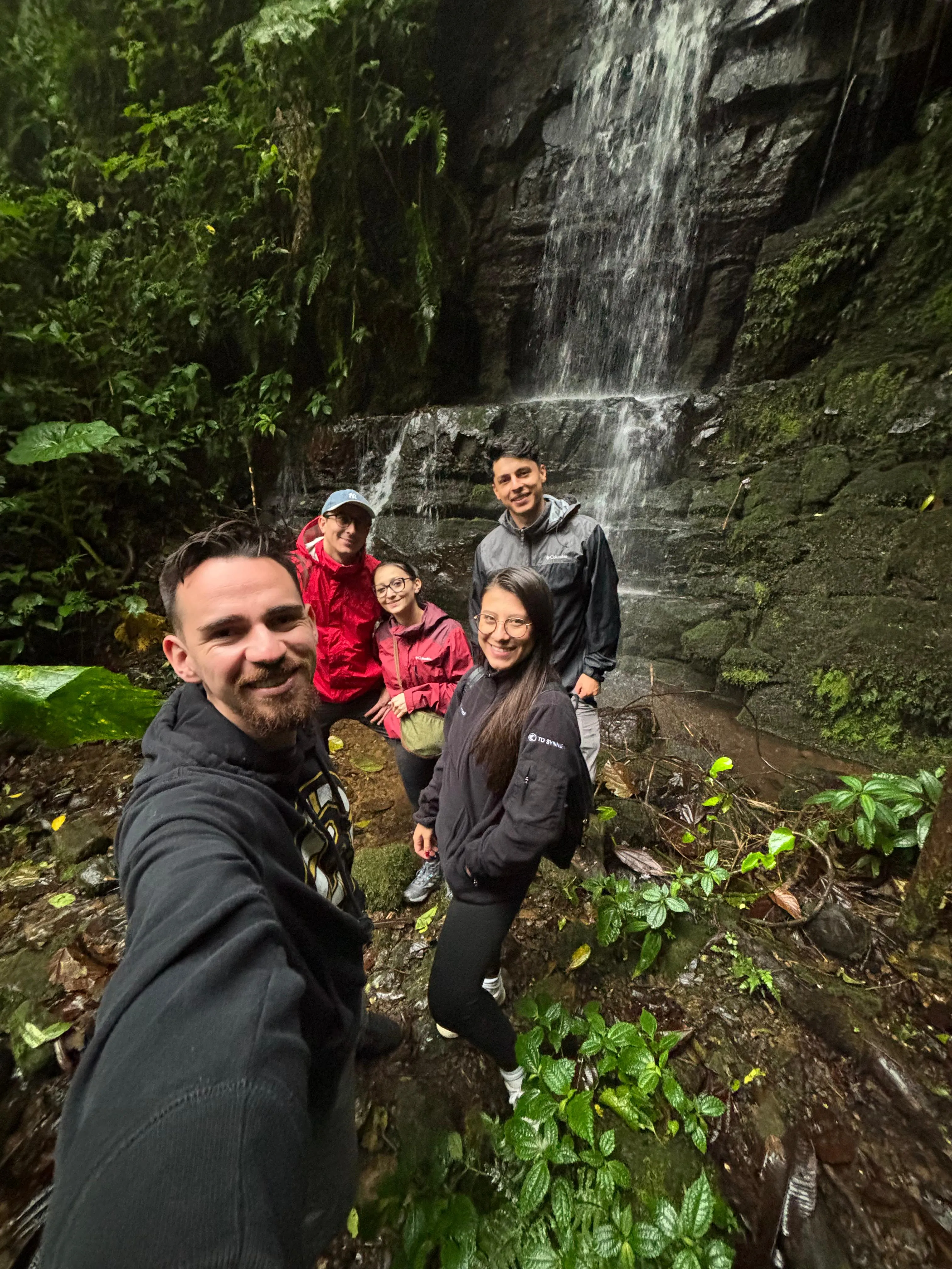 young adults taking a selfie in front of a waterfall